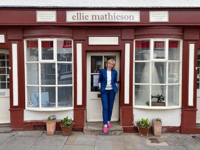 Ellie in front of a red and white store front; this is her store in Presteigne, Wales