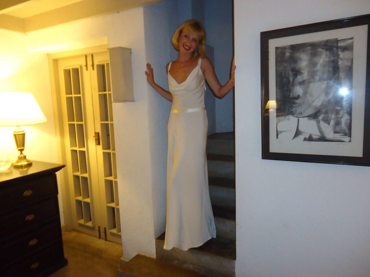 Ellie standing on stairs in a white dress
